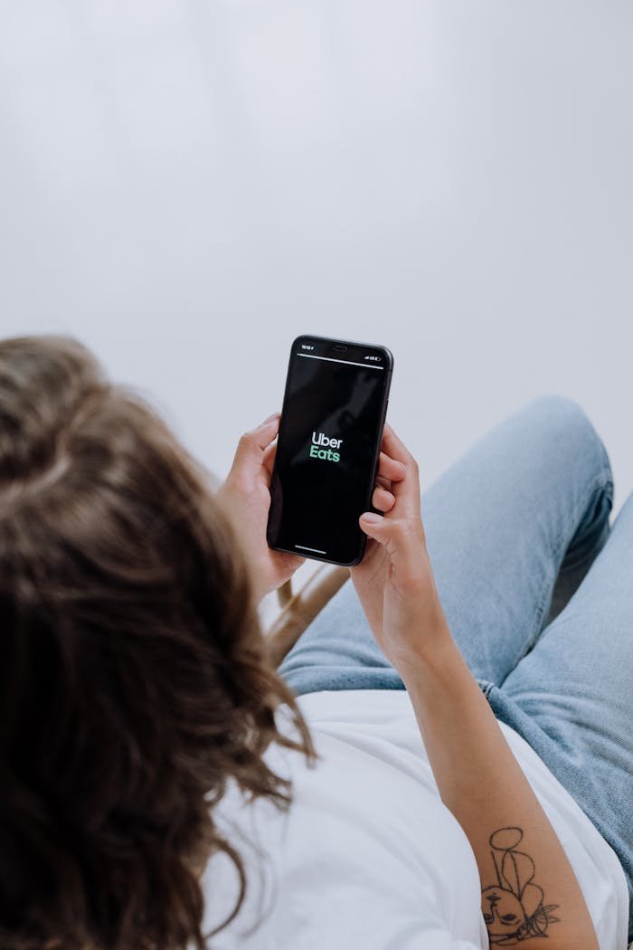 Overhead view of a person using Uber Eats app on a smartphone, showcasing modern technology integration.